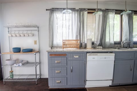 Charming kitchenette with vintage flair – Unique second kitchen or prep area with open shelving and soft curtains.