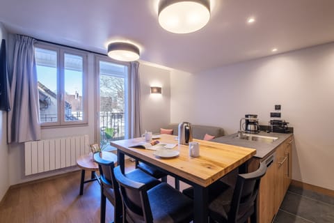 The bright living area features large windows, a cosy sofa bed, and a dining space, creating a comfortable place to relax in this modern apartment.