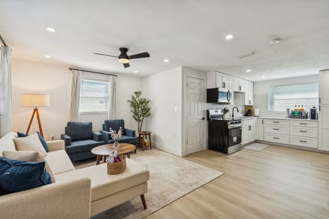 Open-concept living space with cozy seating, large windows, and a ceiling fan for added comfort. The modern kitchen offers full-size appliances and everything you need to cook with ease.