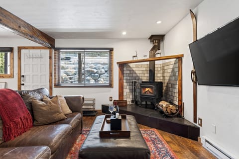 Cozy living room with a wood-burning stove, plush leather seating, and a big-screen TV—perfect for après-ski nights.