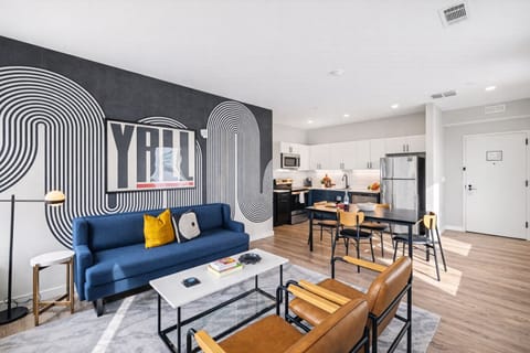 Unit 1: Bright open floor living space featuring a smart flat-screen TV and designer furnishings. Connects to the dining area and kitchen.