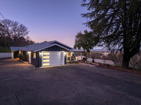 This sleek navy home features warm outdoor lighting, a wide driveway, and a tiered garden path that leads to a private patio overlooking the valley.