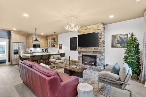 Spacious open-concept living—stone fireplace, big-screen TV, and a chef’s kitchen with bar seating.