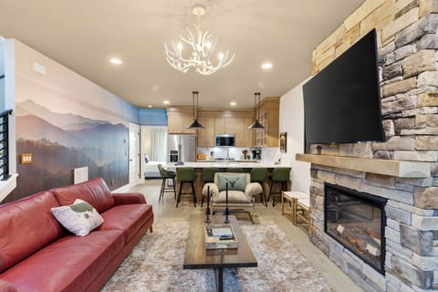 Gather by the stone fireplace—huge TV, cozy seating, and a warm lodge-style vibe.