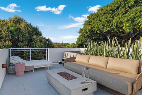 Relax in style on the private rooftop featuring a large  sofa, a modern fire pit, and comfortable sun loungers.