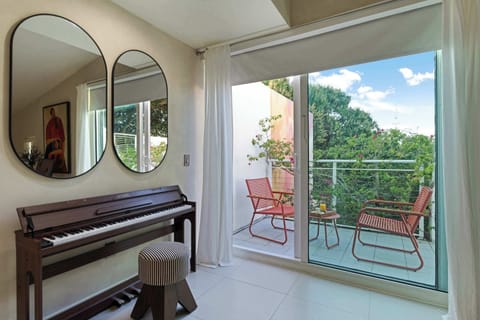 A serene corner featuring a piano and large sliding glass doors that lead to a sunny outdoor terrace with comfortable seating.