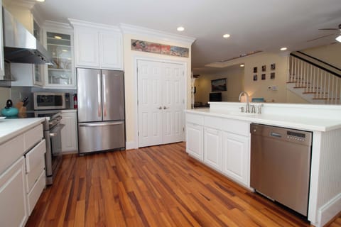 Your chef-worthy kitchen features gleaming stainless steel appliances, elegant white cabinetry, and warm hardwood floors for memorable meal preparation.