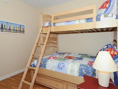 This cozy bedroom features a charming wooden bunk bed adorned with colorful coastal-themed quilts, perfect for beachside adventures.
