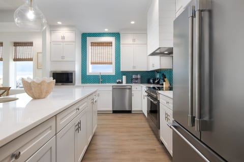 A contemporary kitchen showcases sleek white cabinetry and a vibrant backsplash, perfectly complementing the coastal theme.