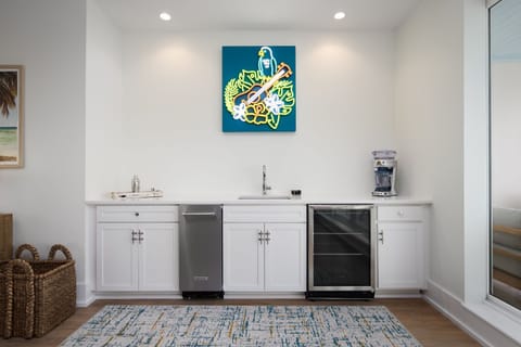 A vibrant bar area features modern appliances and a playful neon artwork that captures the coastal spirit.