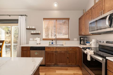 Step into your fully equipped kitchen with warm wood cabinetry, modern appliances, and marble countertops—perfect for preparing home-cooked meals.