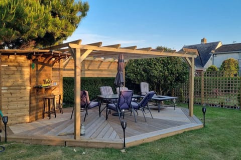 Timber pergola seating area with a table and chairs on a lawn.