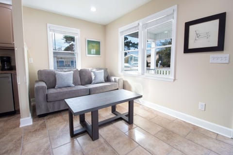 Relax on the plush sofa in your bright living room, where large windows frame peaceful neighborhood views and natural light fills the space.