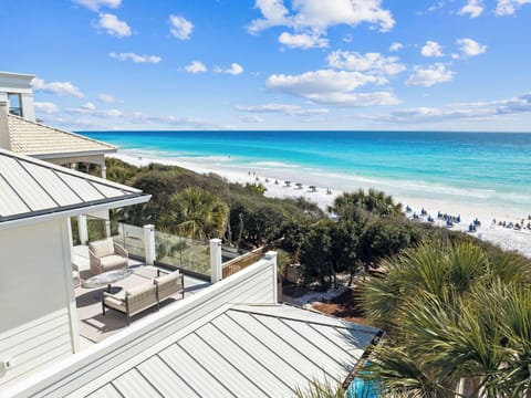 Stunning beachfront property with expansive deck overlooking pristine white sand beach and turquoise waters.