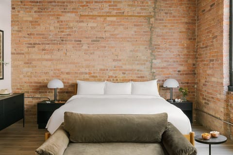 Spacious king bed studio with exposed brick, large windows, and hotel quality linens