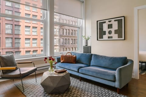Spacious living room with large windows, natural light, and comfortable seating