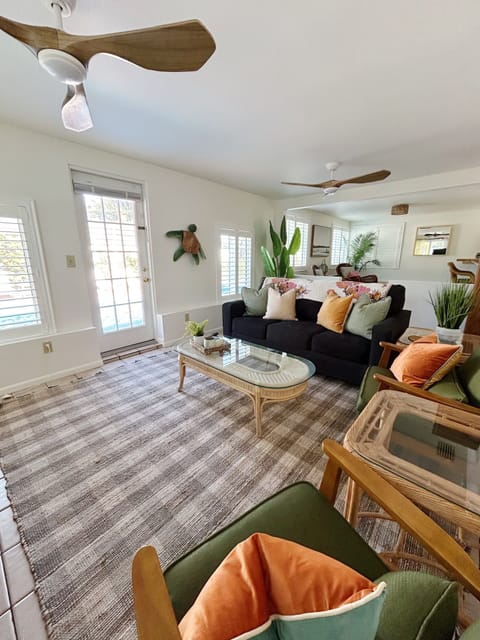colorful living room w/ pull out sofa and access to the back patio w/ pool