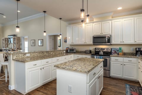 Your dream kitchen awaits with elegant granite countertops, spacious white cabinets, and modern pendant lighting perfect for memorable meals.
