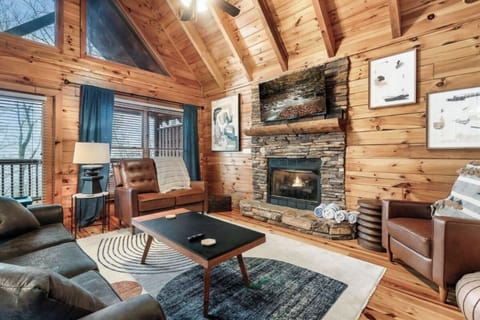 Cozy up by your stone fireplace in this warm cabin living room with leather chairs and rustic charm.
