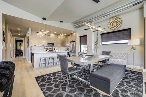 This open-concept layout is perfect for entertaining, featuring a large dining area that flows into the kitchen. The space is highlighted by professional-grade appliances, modern cabinetry, and sculptural pendant lighting.