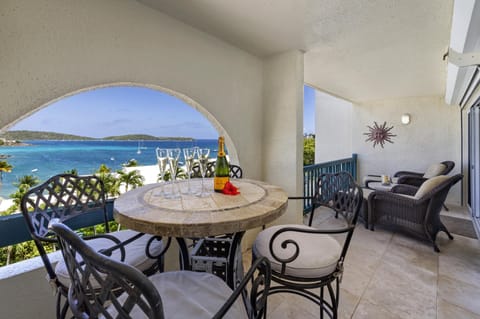 High-top dining table with wrought iron chairs and cushioned wicker lounge seating on covered balcony with incredible view!
