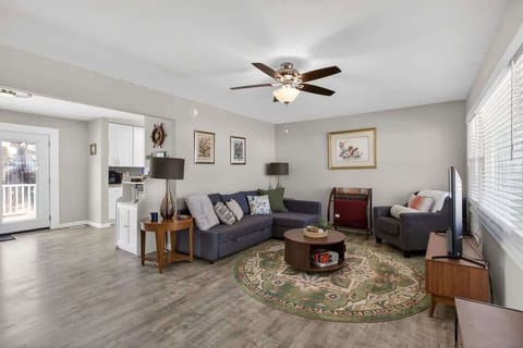 Relax in this sun-filled living room with a cozy sofa, large TV, and neutral tones accented with colorful décor—ideal for movie nights or lounging with family.