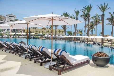 Lounge in the sun with shaded loungers and sparkling water.
