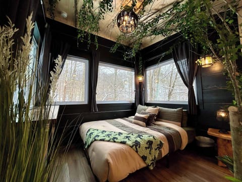 Drift off in a queen bed under a canopy of branches and vines, surrounded by four large windows that fill the space with natural light & views of the surrounding forest. 