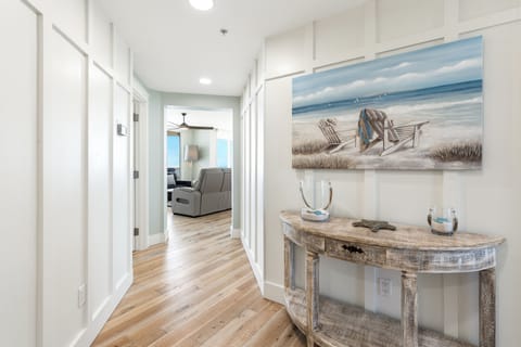 Warm coastal vibes welcome you home through this bright hallway, where beach-themed artwork and rustic furnishings create your perfect seaside retreat.