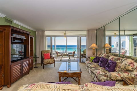 Relax in your bright living room with tropical decor and stunning ocean views through floor-to-ceiling windows opening to your private balcony.
