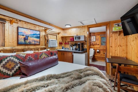 Comfortable studio cabin featuring a cozy bed, kitchenette, dining space, and private bathroom for an easy, relaxing stay.