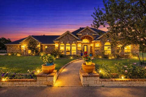 Charming Texas vacation rental with glowing curb appeal, lush lawn, and sunset views