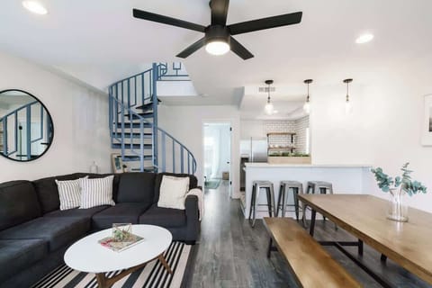 Downstairs living space with large, sectional couch, large dining area, and open kitchen