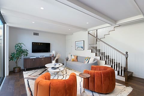 Relax in this stylish, modern living room featuring vibrant accent chairs, and a large flat-screen TV for the ultimate movie night.