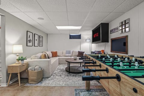 Lower level game room with a super comfy sectional sofa, smart TV, foosball, and board games. The perfect spot for getting cozy watching your favorite show or for the competitive spirits of your group!