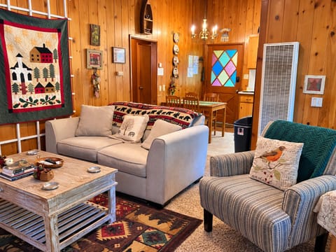 A cozy, wood-paneled living room with comfortable seating, a rustic coffee table, and warm mountain-cabin décor throughout.