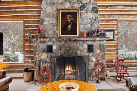 Rustic lodge living room with a roaring stone fireplace, log cabin walls, cozy seating, and warm cabin charm.