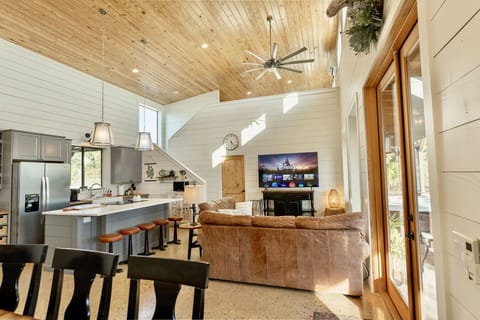 The open-concept home combines modern kitchen, cozy living space, and rustic wood ceilings