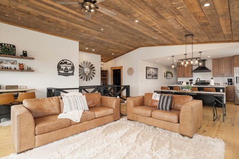 Sink into luxurious leather sofas beneath stunning wood beam ceilings in this open-concept retreat where mountain charm meets modern comfort.