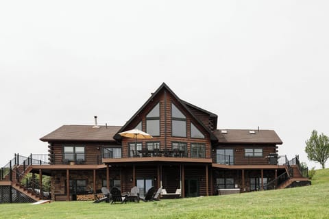 The backyard of this beautiful log cabin is a year-round dream, featuring a full wraparound porch, a cozy fire pit, and do