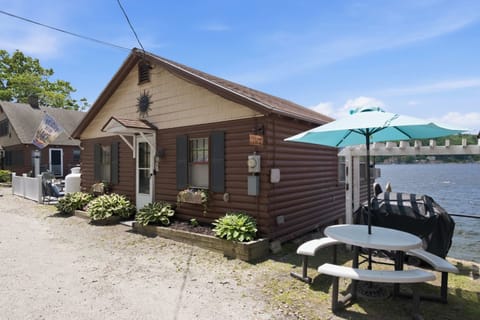 The cottage in summer, sitting right at the water's edge with the mountains behind it.