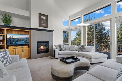 Unwind in your spacious living room where plush seating surrounds a cozy fireplace, while floor-to-ceiling windows frame stunning mountain views.
