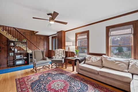 Rich wood paneling, a patterned rug, and plenty of natural light — the living room has the feel of a well-loved New England home.