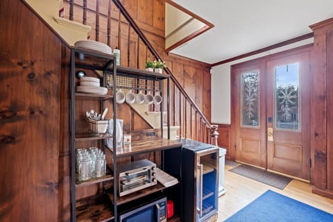 The private entrance with keyless lock opens into the kitchenette area — the open shelving holds everything you need for mornings and simple meals.