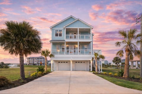 Front view of modern Galveston TX vacation rental with large driveway and elevated coastal home design.