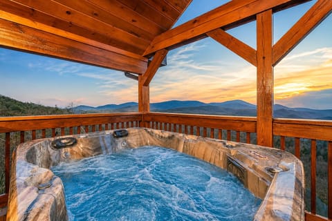 Smoky Mountain cabin hot tub with panoramic mountain views, covered deck seating, and relaxing spa experience at luxury Sevierville TN vacation rental.