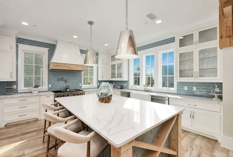 Your culinary dreams come alive in this stunning kitchen with marble island, premium appliances, and charming blue subway tile backsplash.