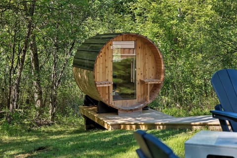 Enjoy the cedar wood barrel sauna's dry heat and gaze at forest through window.
