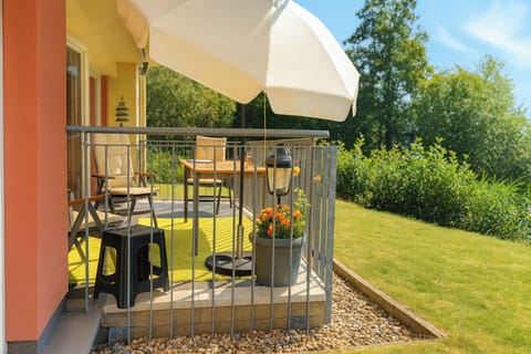 Balcony with table, chairs, and parasol.