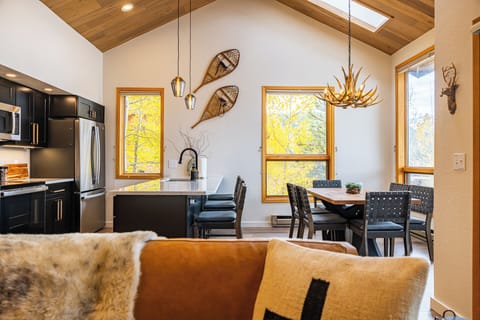 Vaulted Ceiling & Open Layout - Soaring wood-plank ceilings, natural light, and open-concept flow connect the kitchen, dining, and living areas in mountain-modern style.